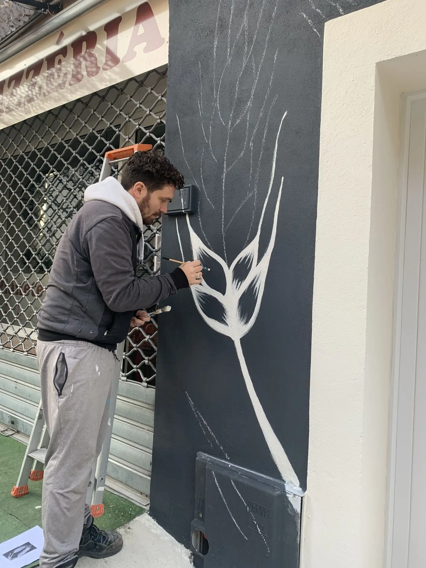 Flo en train de peindre un élément décoratif sur la façade extérieure